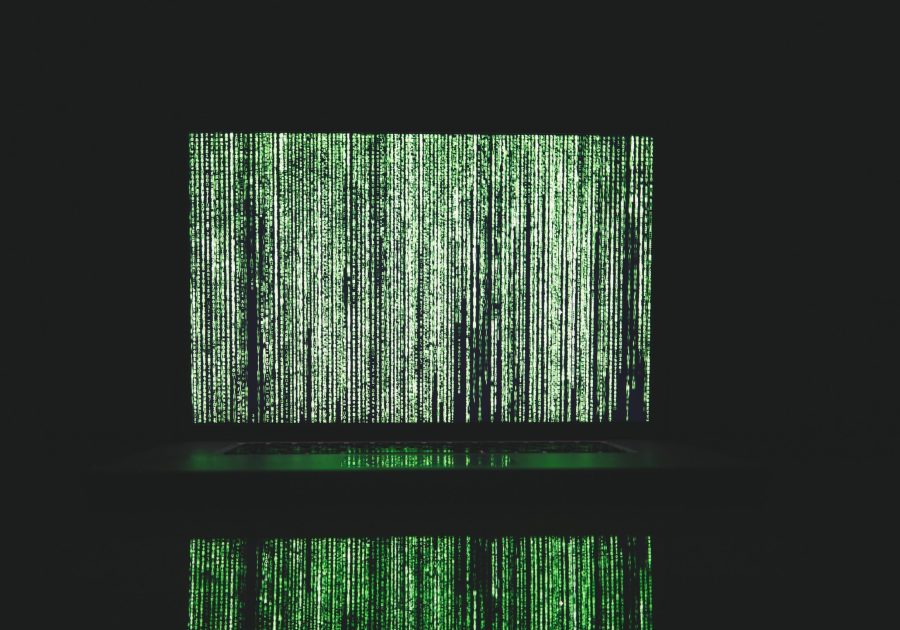 A black background with a laptop screen showing blurred code in green